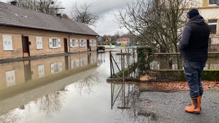 Sven Müller blickt auf ein Haus in Rastatt, das von Wasser eingekesselt ist. Das Hochwasser im Rhein hat teilweise den Stadtteil Plittersdorf überschwemmt.