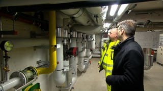 Zwei Experten schauen sich die Anlange der Heizzentrale an. Die Gemeinde Kronau hat schon 2018 ein Modellprojekt für ein Nahwärmekonzept auf Basis erneuerbarer Energien entwickelt.