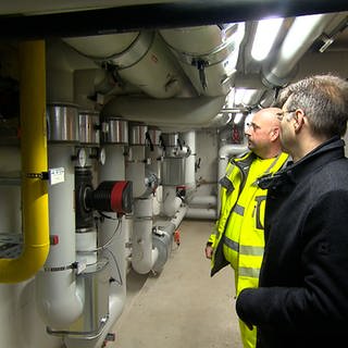 Zwei Experten schauen sich die Anlange der Heizzentrale an. Die Gemeinde Kronau hat schon 2018 ein Modellprojekt für ein Nahwärmekonzept auf Basis erneuerbarer Energien entwickelt.