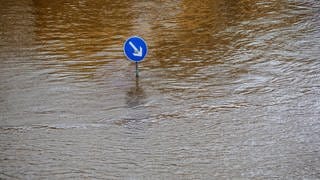 Ein Straßenschild steht im Hochwasser (Symbolbild)