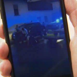 Mögliche Polizeigewalt auf einem Handybildschirm zu sehen