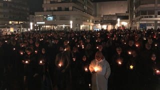 Menschen in Pforzheim gedenken am Abend mit einer Kerze in der Hand den Opfern der Bomennacht am 23. Februar 1945