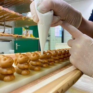 In Bad Liebenzell im Landkreis Calw hauchen Mitarbeiterinnen und Mitarbeiter kleinen Osterhasen aus Marzipan Leben ein