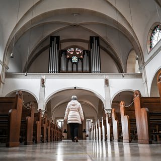 Symbolbild: Eine Frau verlässt eine Kirche, deren Bänke leer sind. Die Evangelische Landeskirche in Baden hat im vergangenen Jahr mehr als 31.000 Mitglieder verloren. 