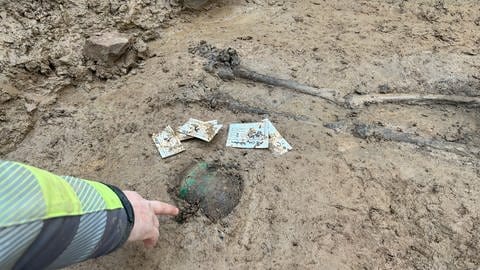 Der Grabungsleiter zeigt auf den Schädel eines Skeletts, das auf einem unbekannten Friedhof in Karlsruhe Durlach gefunden wurde