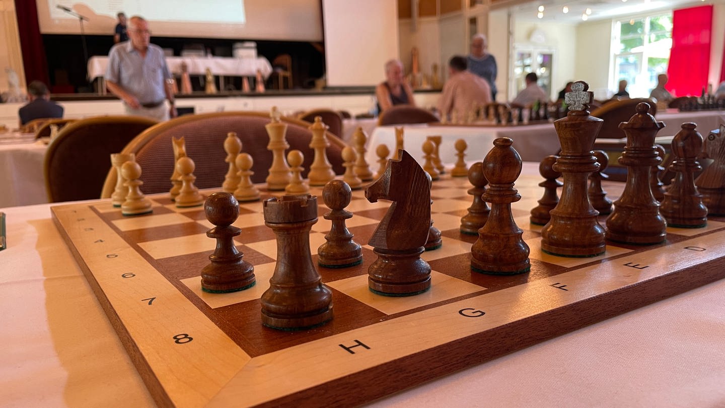 Ein aufgebautes Schachbrett vor dem Hintergrund eines Schachturniers