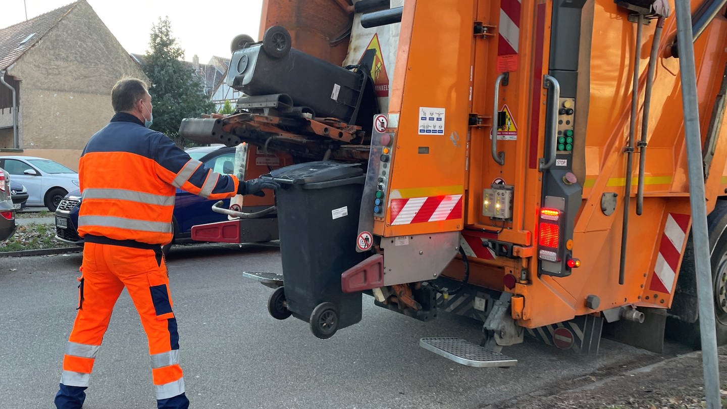 Rund 70 Mitarbeiter sind jeden Tag für Stadtreinigung und Müllabfuhr in Karlsruhe unterwegs. Müllmann hinter einem Müllauto bei der Arbeit.