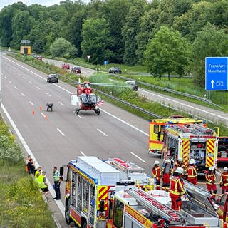 Ein auf der Fahrbahn der A5 gelandeter Rettungshubschrauber und Rettungskräfte nach einem Unfall