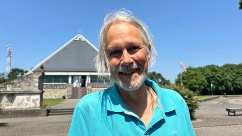 Ein Mann steht vor der Autobahnkirche Baden-Baden. Die Kirche steht auf einem Rasthof für Reisende der A5.