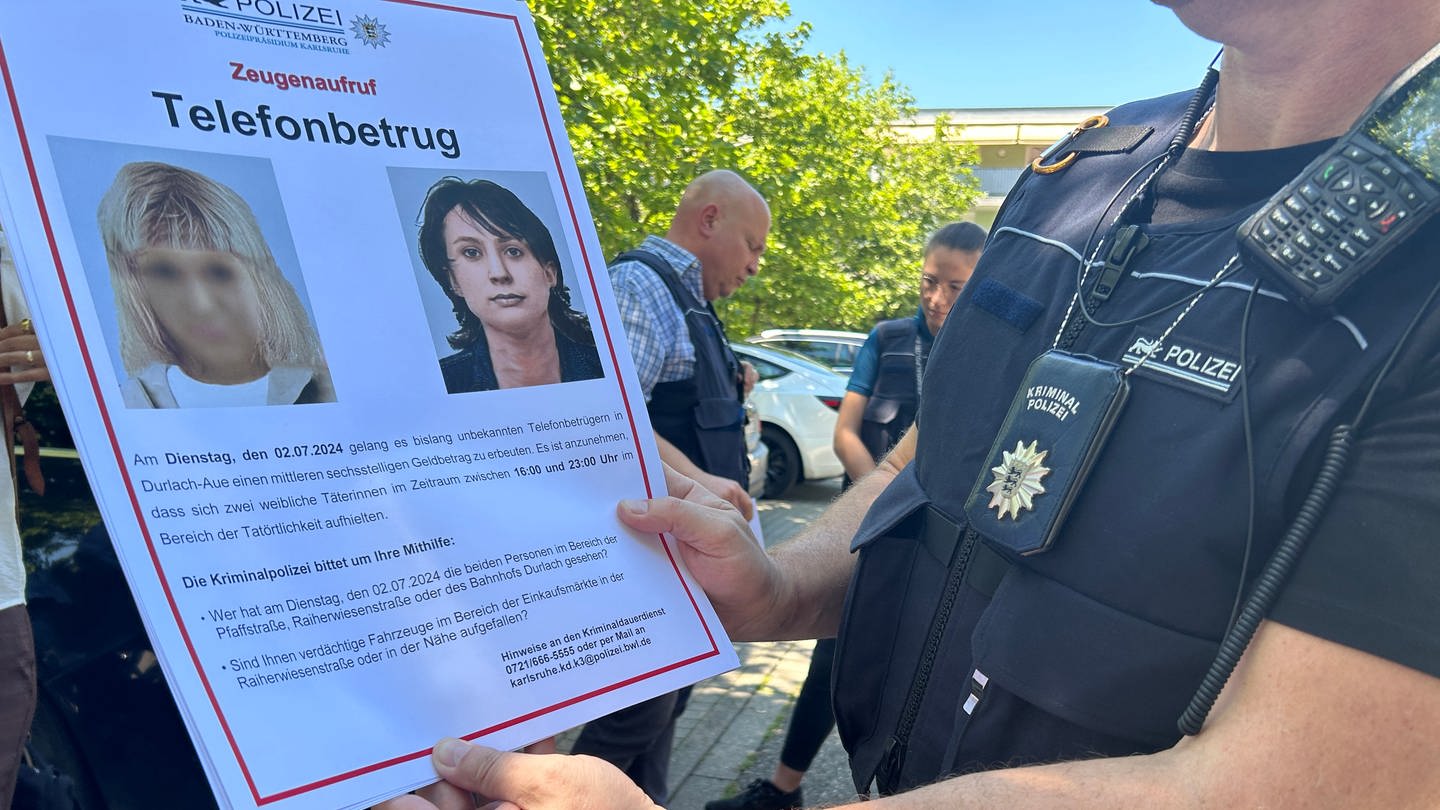Ein Hauptkommissar der Polizei zeigt ein Plakat mit dem Phantombild zweier mutmaßlicher Telefonbetrügerinnen in Karlsruhe.