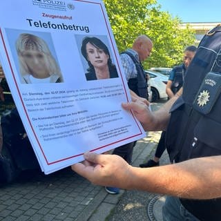 Ein Hauptkommissar der Polizei zeigt ein Plakat mit dem Phantombild zweier mutmaßlicher Telefonbetrügerinnen in Karlsruhe.