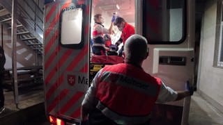 Ein Patient mit Herzstillstand wird eingeliefert. Er liegt im Rettungswagen - Ersthelfer um ihn herum. 