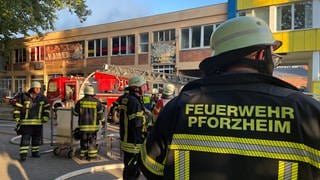 Feuerwehrmänner sammeln sich vor dem Gebäude - die Löscharbeiten laufen noch