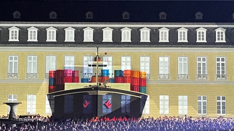 Ein riesiges Frachtschiff wird auf die Fassade des Karlsruher Schlosses projiziert.