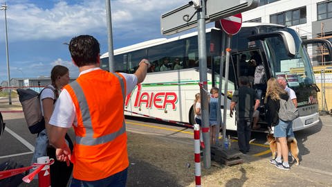 Ein Mitarbeiter der Deutschen Bahn weist die Reisenden ihre Busse am Bahnhof in Baden-Baden zu.