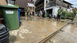 Anwohner fegen nach dem Hochwasser den Schlamm von einem Grundstück in Heidelsheim.