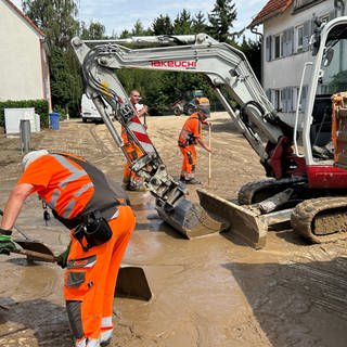 Mitarbeiter der Stadt Bruchsal helfen bei der Beiseitigung des Schlamms mit Bagger und Schaufeln. Das Unwetter im Kreis Karlsruhe hat Spuren hinterlassen. 