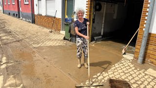 Eine Anwohnerin schiebt Schlamm von ihrem Grundstück in Heidelsheim