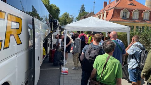 Menschen laden Gepäck in Busse des Schienenersatzverkehrs am Hauptbahnhof in Karlsruhe.