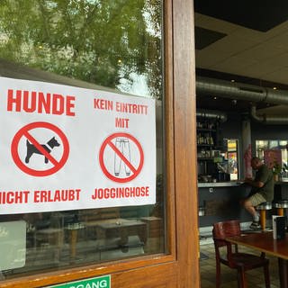 Verbotsschilder weisen schon am Eingang darauf hin: Jogginghosen sind in einem Café in Pforzheim unerwünscht