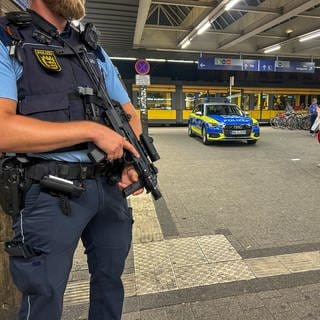 Polizeieinsatz am Abend nach einem Messerangriff am Karlsruher Hauptbahnhof. Ein bewaffneter Polizist steht vor dem Haupteingang.