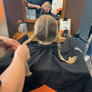 Emil aus Forbach spendet seine Haare für krebskranke Kinder. Die Friseurin Christine Schmidt flechtet seine Haare vorher zu Zöpfen.