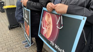 Schilder, mit denen Abtreibungsgegner vor Pro Familia in Pforzheim gegen Abtreibungen protestieren.