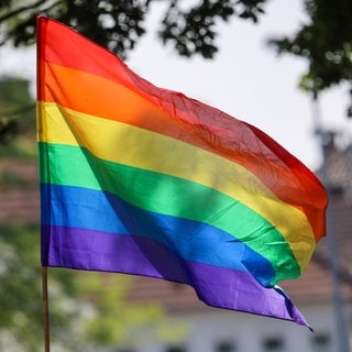 Symbolbild: Eine Regenbogenfahne weht im Wind.