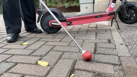 Ein Blindenstock vor einem E-Scooter in Pforzheim.