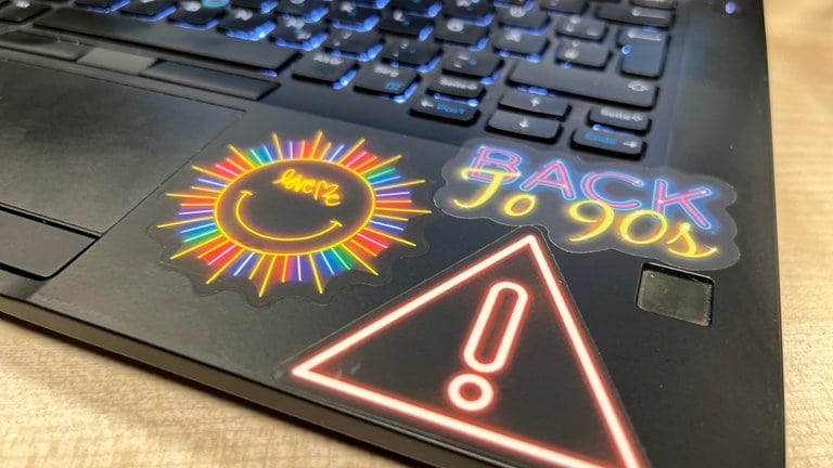 Auf einem Laptop sieht man mehrere Aufkleber - etwa die Aufschrift "Back to the 90s".