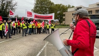 Beschäftigte der S-Bahn in Karlsruhe halten bei einem Warnstreik Flaggen der Gewerkschaft ver.di und tragen gelbe Westen.