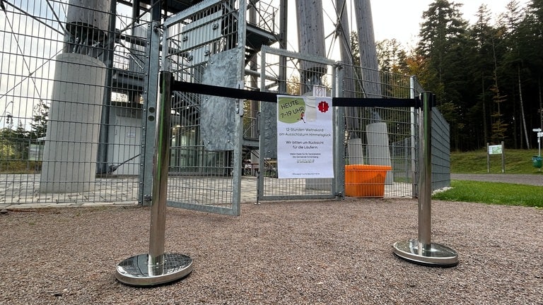 Ein Schild weist vor dem Aussichtsturm "Himmelsblick" in Schömberg auf den Weltrekordversuch hin. Der Turm ist auch währenddessen geöffnet.