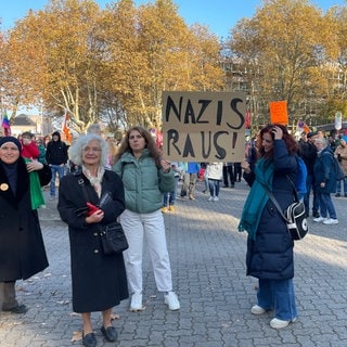 Demonstranten halten ein Plakat hoch. 