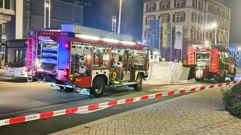 Einsatzfahrzeuge der Feuerwehr stehen in Altensteig (Kreis Calw) am Unfallort: Eine Frau wurde unter einem Bus eingeklemmt und tödlich verletzt.