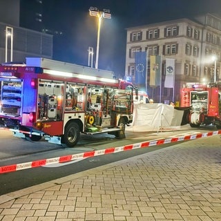 Einsatzfahrzeuge der Feuerwehr stehen in Altensteig (Kreis Calw) am Unfallort: Eine Frau wurde unter einem Bus eingeklemmt und tödlich verletzt.