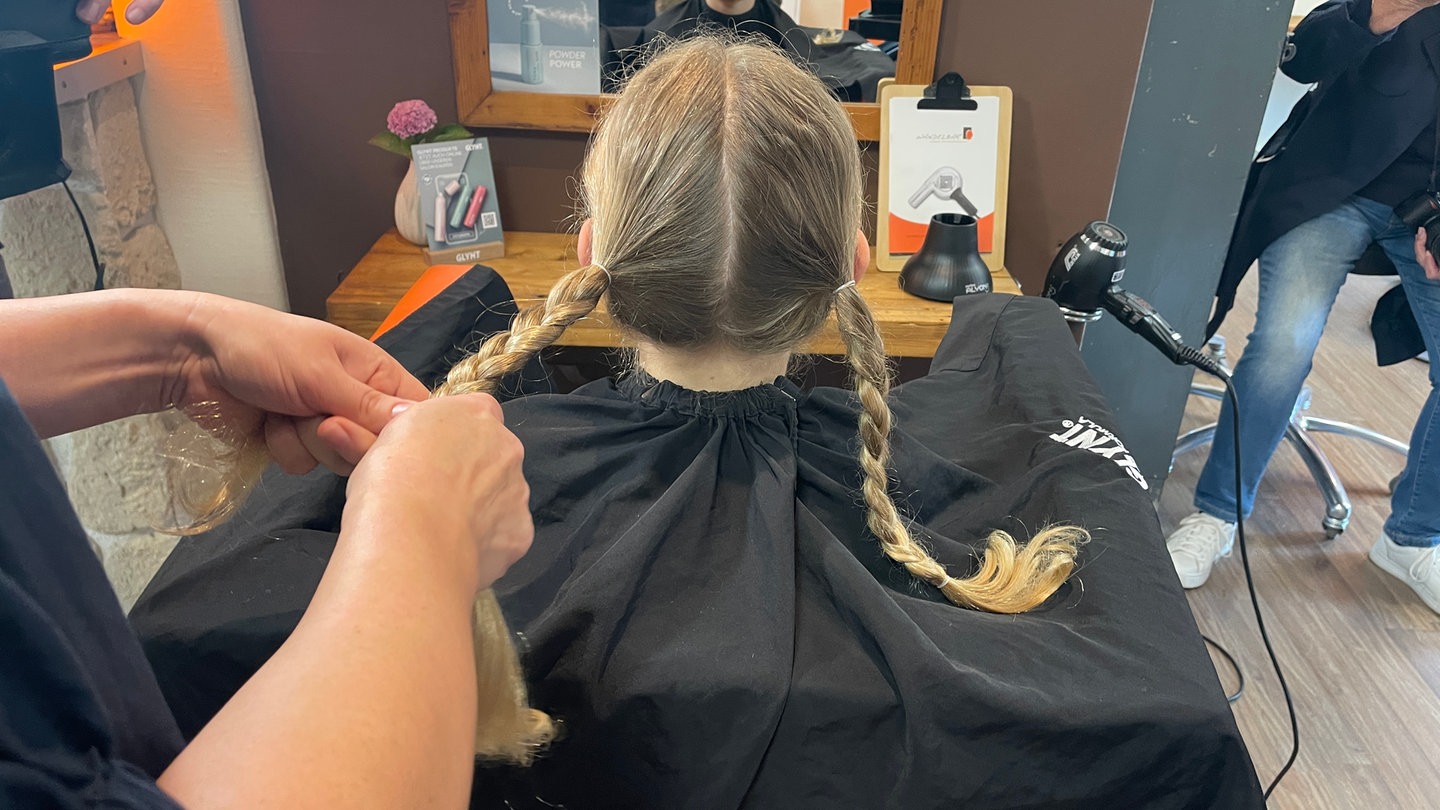 Emil aus Forbach spendet seine Haare für krebskranke Kinder. Die Friseurin Christine Schmidt flechtet seine Haare vorher zu Zöpfen.