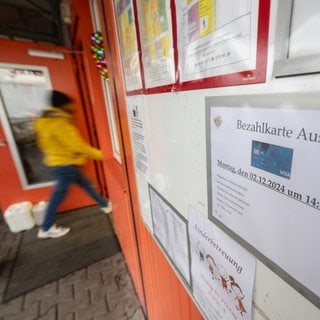 Ein Schild weist in der Erstaufnahmeeinrichtung Eggenstein-Leopoldshafen (Landkreis Karlsruhe) auf die Ausgabe von Bezahlkarten hin. 