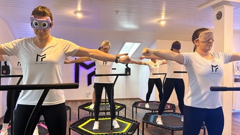 Die Fitness Jumper aus Ettlingen stehen auf dem Trampolin und tragen verschiedene Masken.