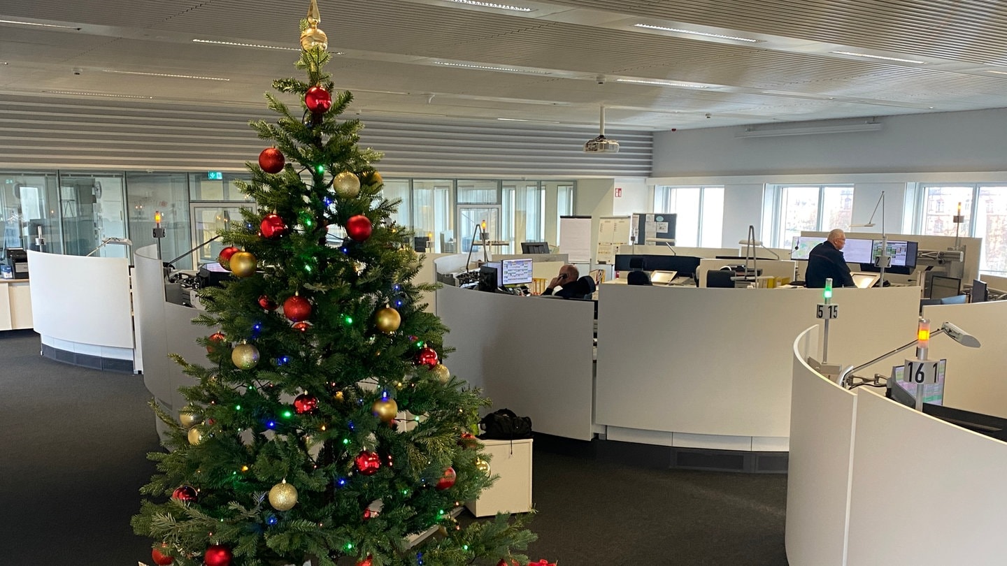 Ein bunt geschmückter Weihnachtsbaum, unter dem viele Geschenke liegen, steht im Büro der Notrufzentrale Karlsruhe.