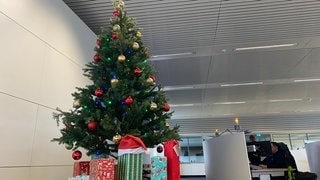 Ein bunt geschmückter Weihnachtsbaum, unter dem viele Geschenke liegen, steht im Büro der Notrufzentrale Karlsruhe.