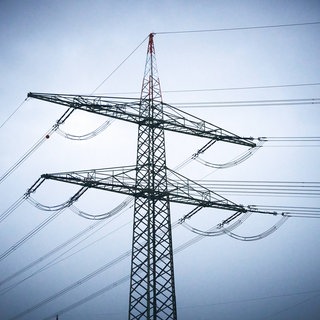 Strommast vor blauem Himmel. Ein Stromausfall legte Ortsteile von Rastatt lahm.