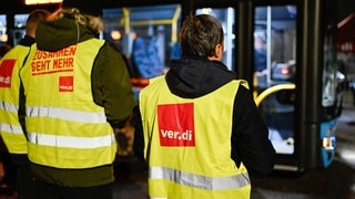 Streikende stehen bei einem Warnstreik der Gewerkschaft ver.di am Gelände der SWEG (Südwestdeutsche Landesverkehrs-GmbH) vor einem Bus.