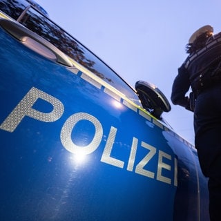 Eine Polizistin steht neben einem Streifenwagen.