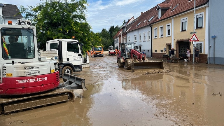 Baustellenfahrzeuge fahren durch die Schlammmassen in Heidelsheim