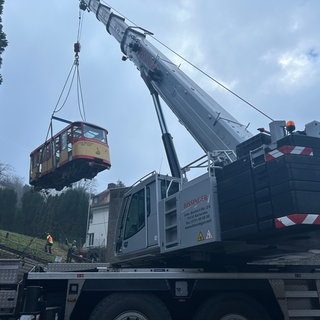 Abbau der Turmbergbahn: Ein Kran hebt den ersten Wagen der Turmbergbahn in Karlsruhe von den Schienen. 