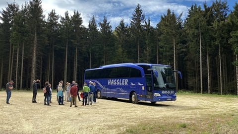 Besuchergruppe und Reisebus im Wald von Lauterstein. Dort informieren sich die Reisenden über den Windpark.