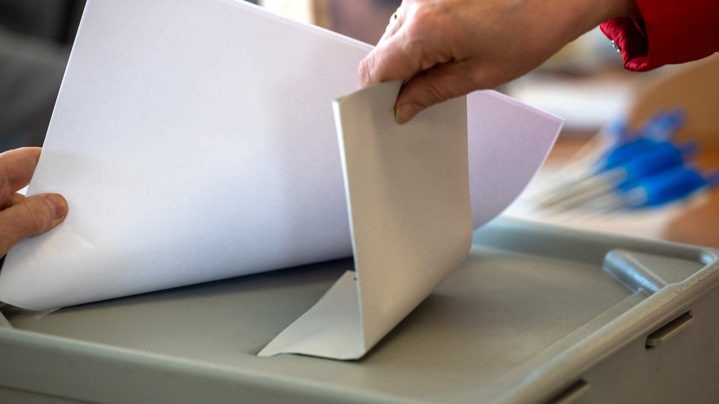 Frau steckt Stimmzettel in Wahlurne