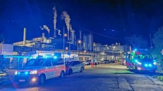 Im Hintergrund ist eine Fabrik zu sehen, im Vordergrund stehen mehrere Einsatzfahrzeuge.