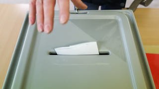 Stimmzettel wird in in Wahlurne geworfen