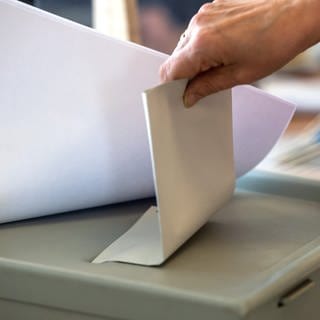 Frau steckt Wahlzettel in Urne